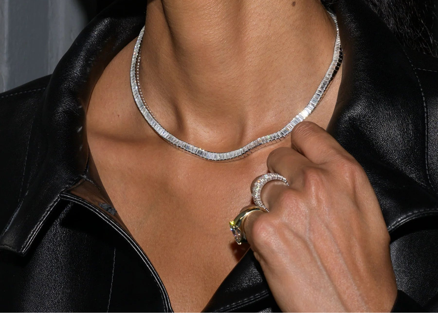 Close-up of a person wearing a silver necklace and ring.